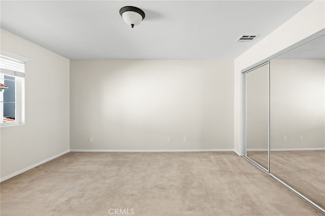 unfurnished bedroom featuring light colored carpet and a closet