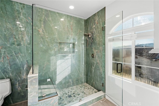 bathroom featuring tiled shower and toilet