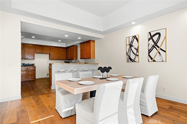 dining room with a raised ceiling and light hardwood / wood-style floors