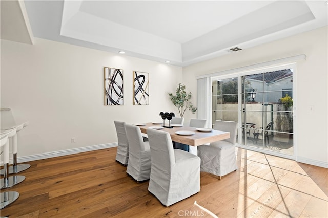 dining space featuring a raised ceiling and hardwood / wood-style floors