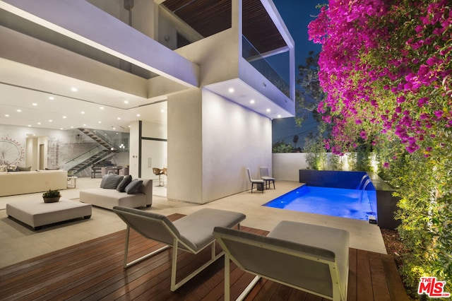 view of pool featuring pool water feature, a deck, a patio, and outdoor lounge area