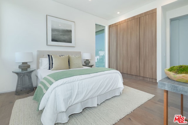 bedroom with light hardwood / wood-style floors and a closet