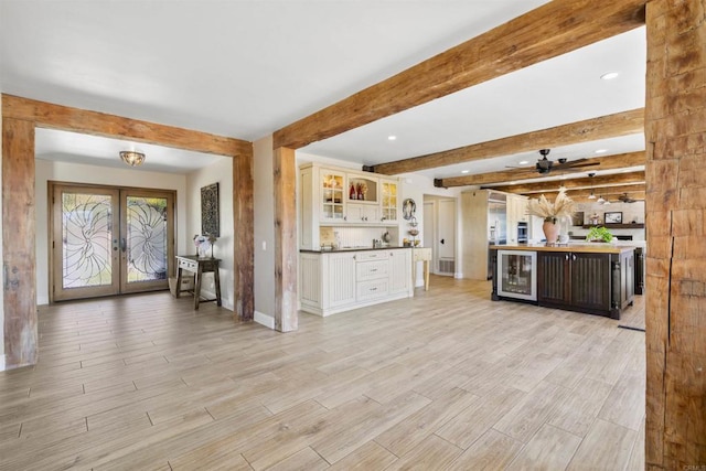 kitchen with white cabinetry, beverage cooler, french doors, and beamed ceiling