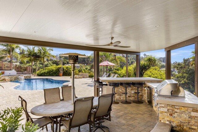 view of pool with an in ground hot tub, a bar, exterior kitchen, ceiling fan, and a patio area