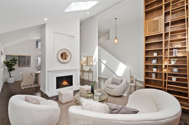 living area featuring recessed lighting, lofted ceiling with skylight, wood finished floors, a lit fireplace, and baseboards