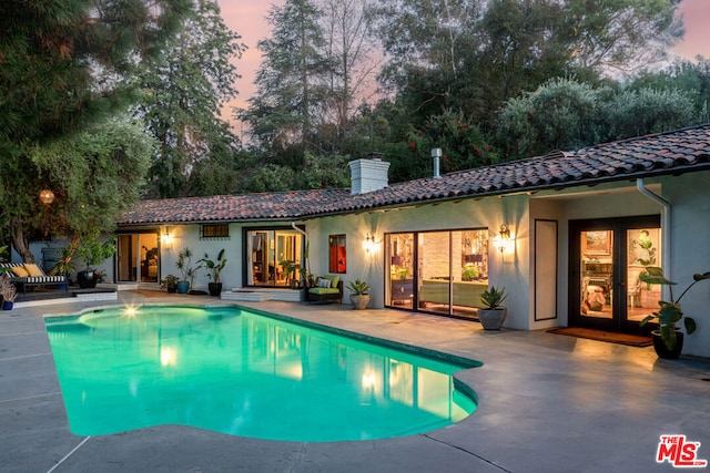 pool at dusk featuring a patio