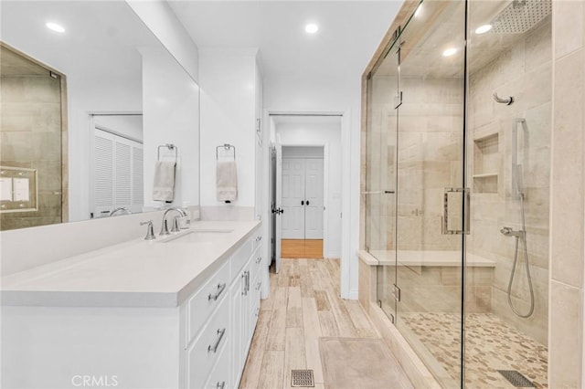 bathroom with hardwood / wood-style flooring, vanity, and walk in shower