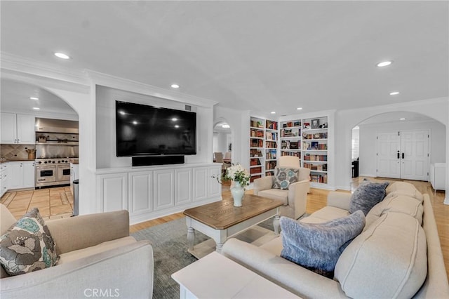 living room with light hardwood / wood-style flooring, crown molding, and built in features