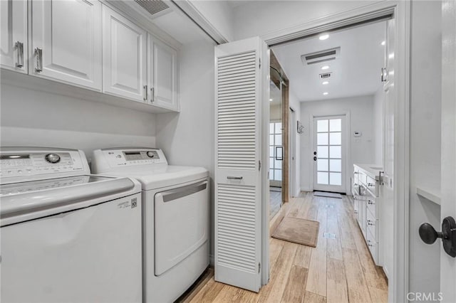 laundry area featuring light hardwood / wood-style flooring, independent washer and dryer, and cabinets