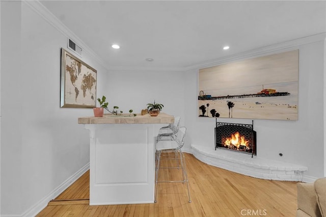 bar with a fireplace, crown molding, and hardwood / wood-style flooring