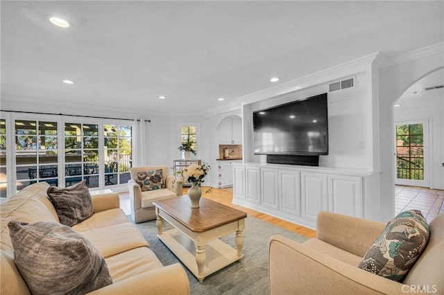 living room with light hardwood / wood-style flooring, plenty of natural light, and ornamental molding