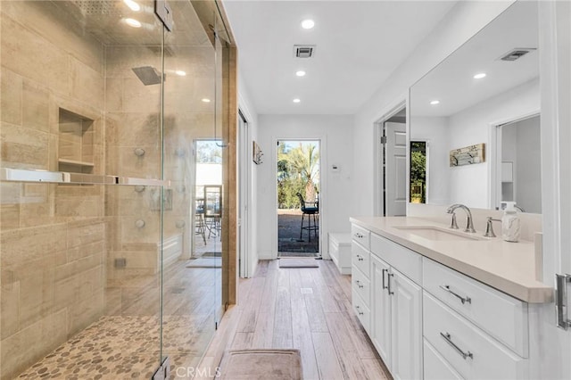 bathroom with hardwood / wood-style floors, vanity, and walk in shower