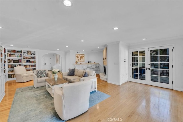 living room featuring light hardwood / wood-style floors, french doors, built in features, and ornamental molding