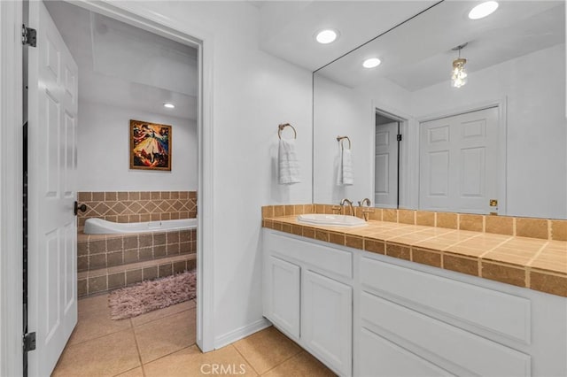 bathroom with tile patterned floors, vanity, and tiled tub