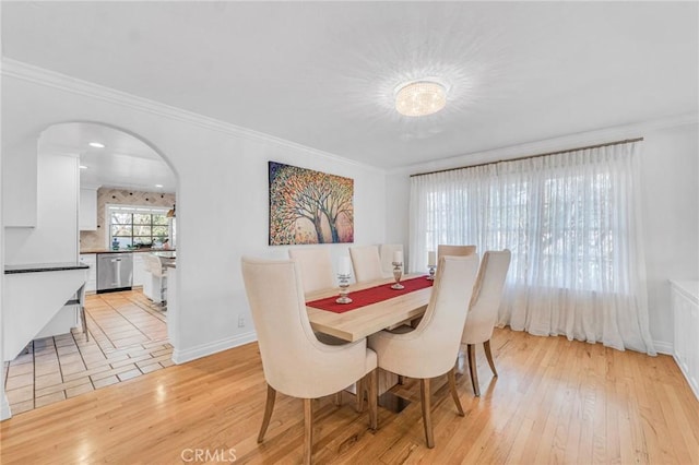 dining space with crown molding and light hardwood / wood-style floors