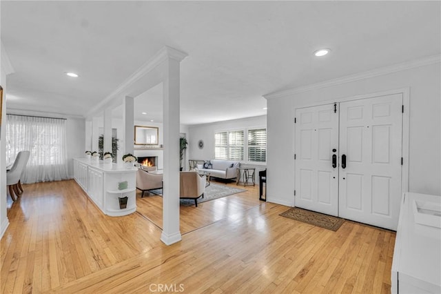 foyer entrance with crown molding and light hardwood / wood-style floors