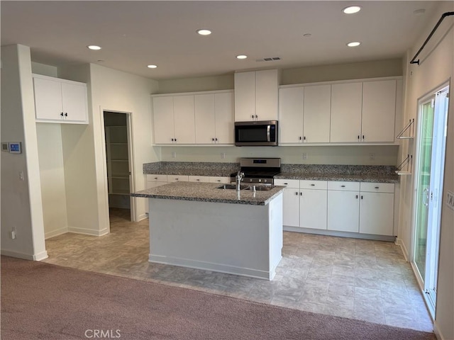 kitchen with white cabinetry, stainless steel appliances, and a kitchen island with sink