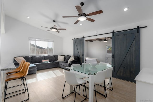 dining area featuring light wood-type flooring, plenty of natural light, lofted ceiling, and a barn door