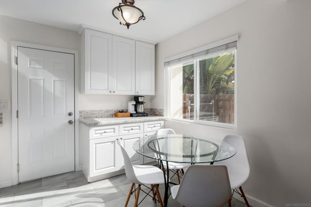 kitchen with white cabinetry, light tile patterned floors, and light stone countertops