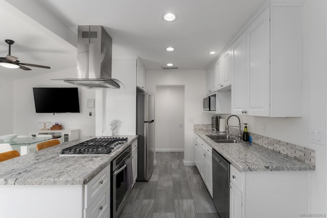 kitchen featuring sink, white cabinets, light stone counters, island range hood, and stainless steel appliances