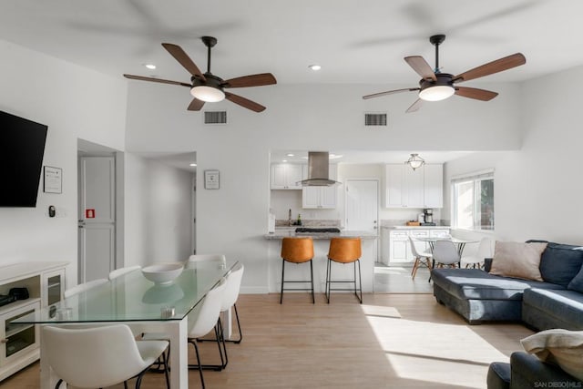 living room with light wood-type flooring, ceiling fan, and high vaulted ceiling