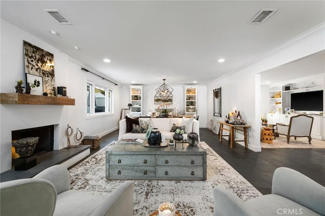 living room with built in shelves, dark hardwood / wood-style floors, and ornamental molding