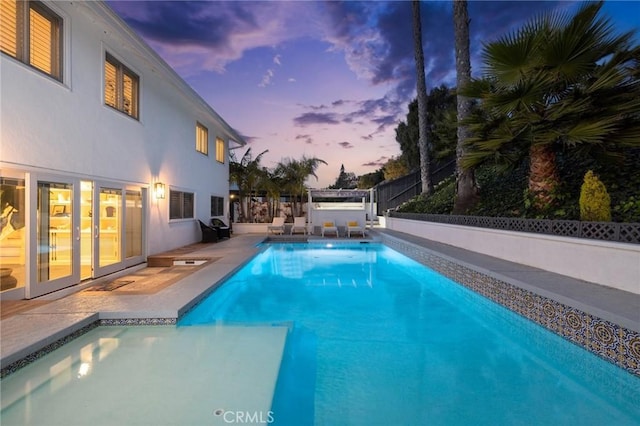 pool at dusk featuring a patio area