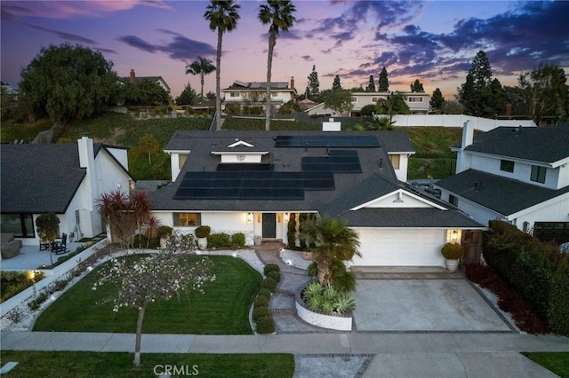 view of front of home with a garage, a yard, and solar panels