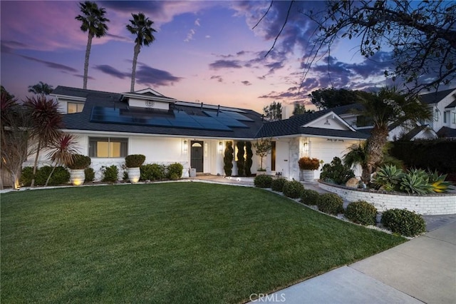 view of front of home featuring a garage, a yard, and solar panels