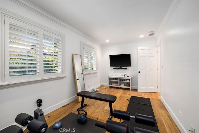 exercise area with light wood-type flooring and crown molding