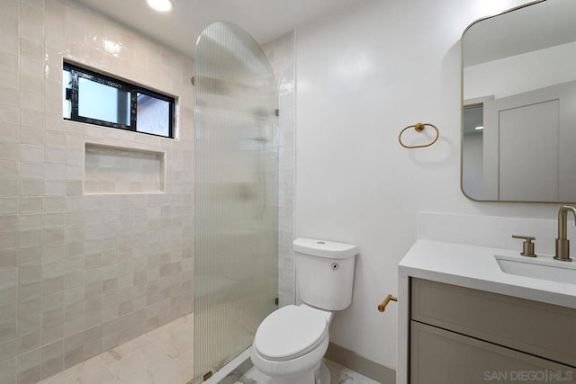 bathroom with tiled shower, toilet, and vanity