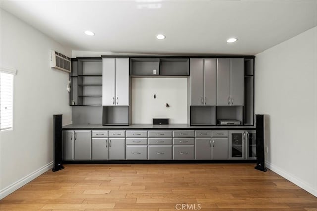 kitchen featuring light wood-type flooring, a wall unit AC, mail boxes, and gray cabinets