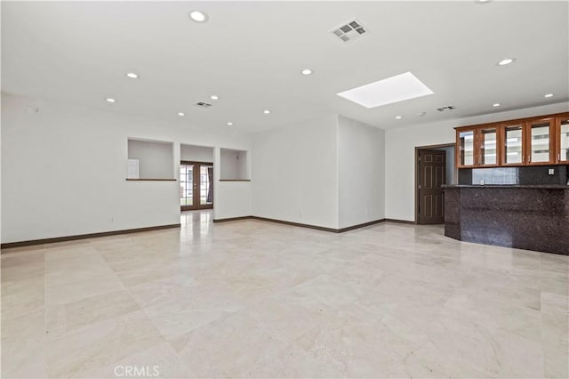 unfurnished living room featuring a skylight and french doors