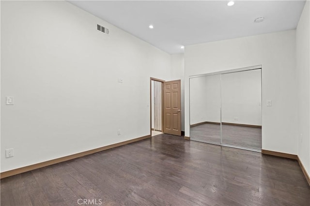 unfurnished bedroom featuring a closet and dark wood-type flooring