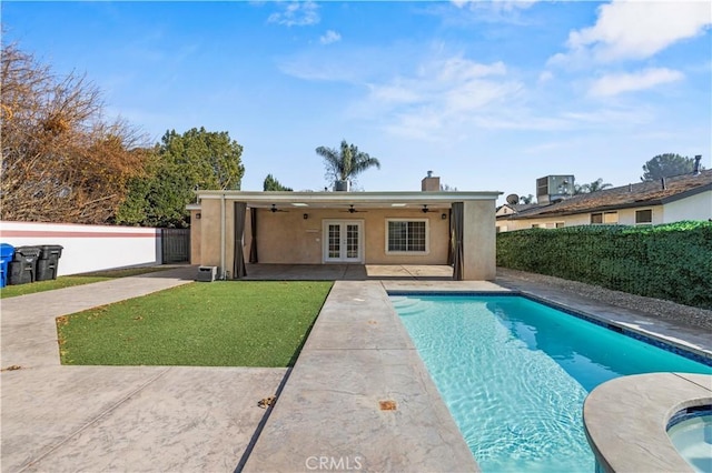 view of swimming pool featuring ceiling fan, french doors, a lawn, and a patio area