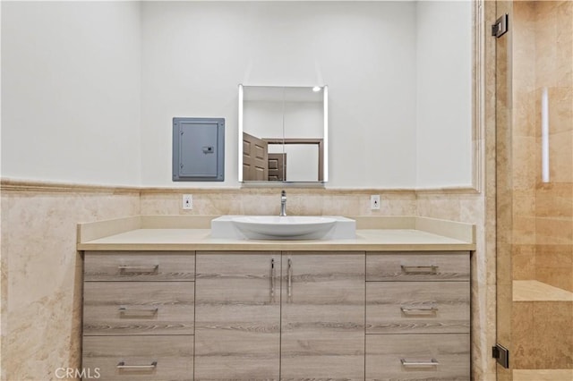 bathroom with tile walls, electric panel, vanity, and walk in shower