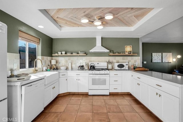 kitchen featuring white appliances, wooden ceiling, white cabinetry, wall chimney range hood, and sink