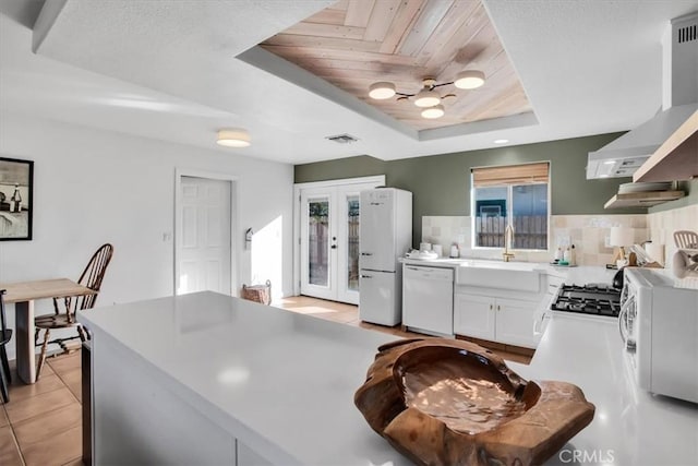 kitchen featuring white appliances, wood ceiling, white cabinetry, sink, and a raised ceiling