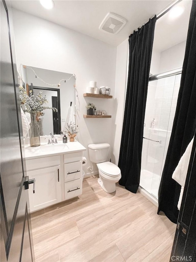 bathroom featuring a shower with door, hardwood / wood-style floors, toilet, and vanity