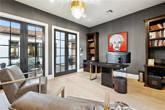 home office with french doors, an inviting chandelier, light hardwood / wood-style floors, and a wealth of natural light