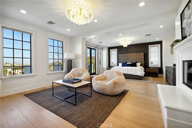 bedroom featuring a chandelier, light hardwood / wood-style floors, and multiple windows