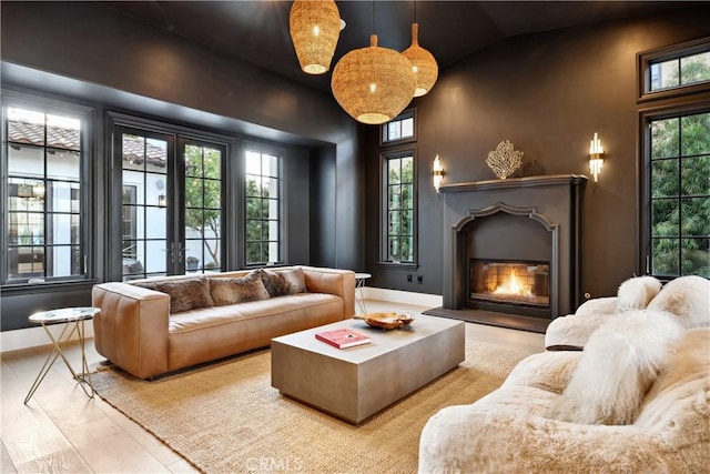 living room with baseboards, french doors, a wealth of natural light, and a glass covered fireplace