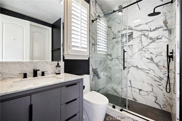 bathroom with a marble finish shower, vanity, toilet, and backsplash