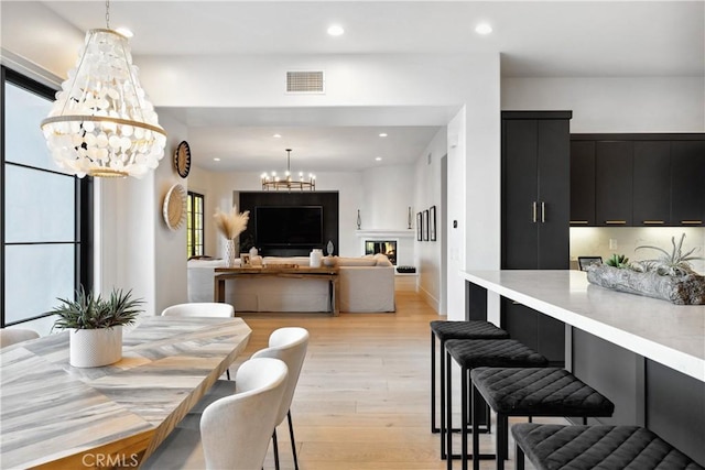 dining area with light wood-style floors, recessed lighting, visible vents, and a notable chandelier