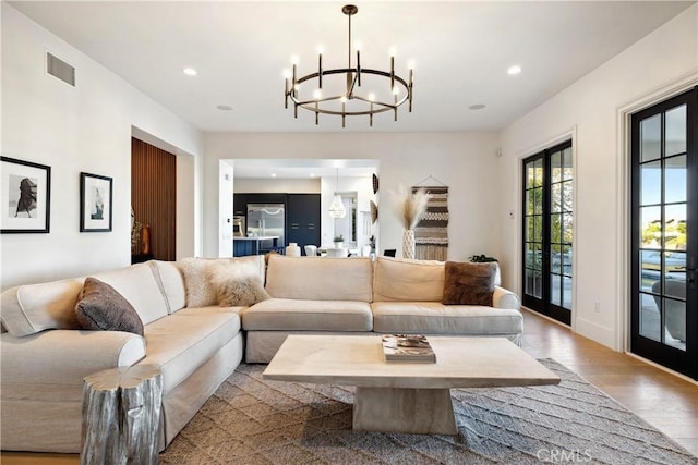 living room featuring french doors, light hardwood / wood-style flooring, and a notable chandelier