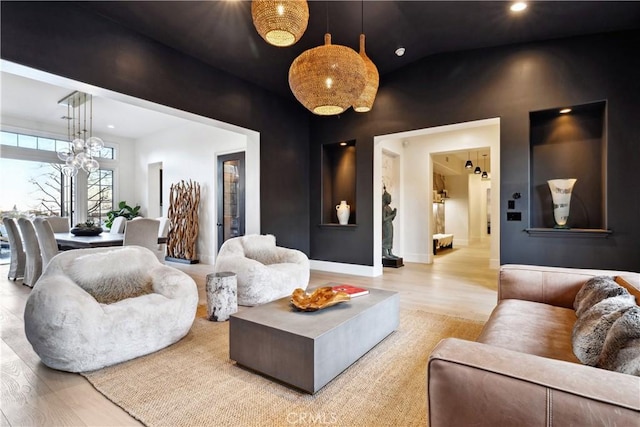 living room with an inviting chandelier, vaulted ceiling, and light wood-type flooring