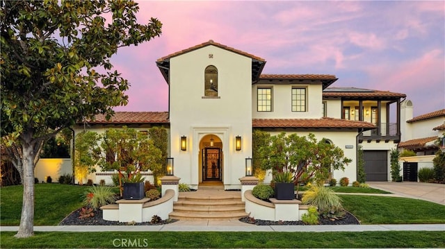 mediterranean / spanish-style home with driveway, stucco siding, roof mounted solar panels, and a yard