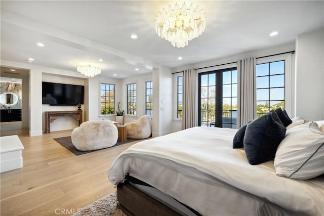 bedroom with french doors, a chandelier, and light hardwood / wood-style floors