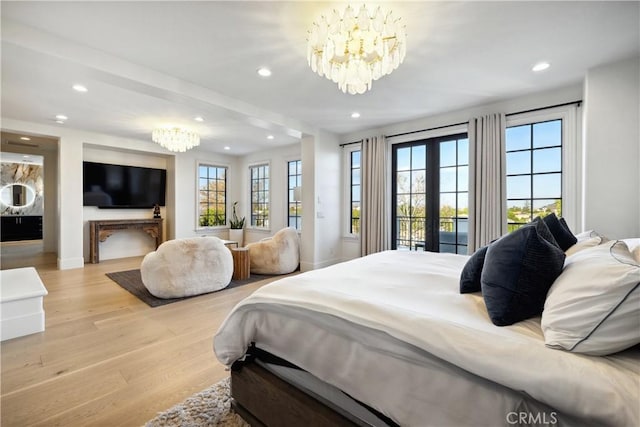 bedroom with light wood-type flooring, french doors, a notable chandelier, and recessed lighting