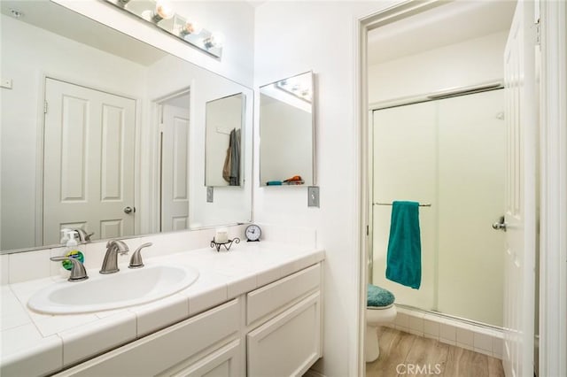 bathroom featuring vanity, a shower with shower door, toilet, and hardwood / wood-style flooring